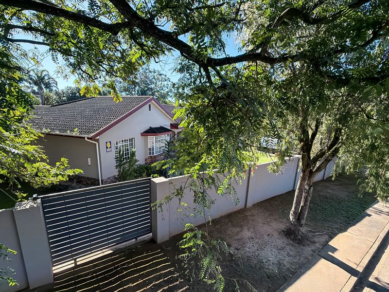 Front view of a residential property featuring a tiled roof, bay window, and a secure boundary wall with a sliding gate.