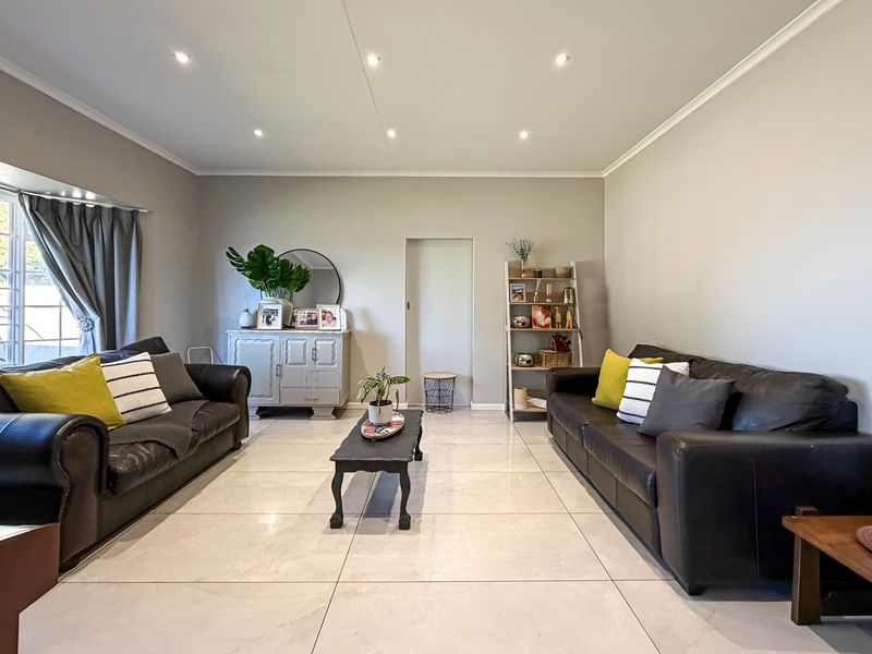 A well-maintained living room featuring large format porcelain floor tiles, recessed downlighting, and neutral wall finishes.