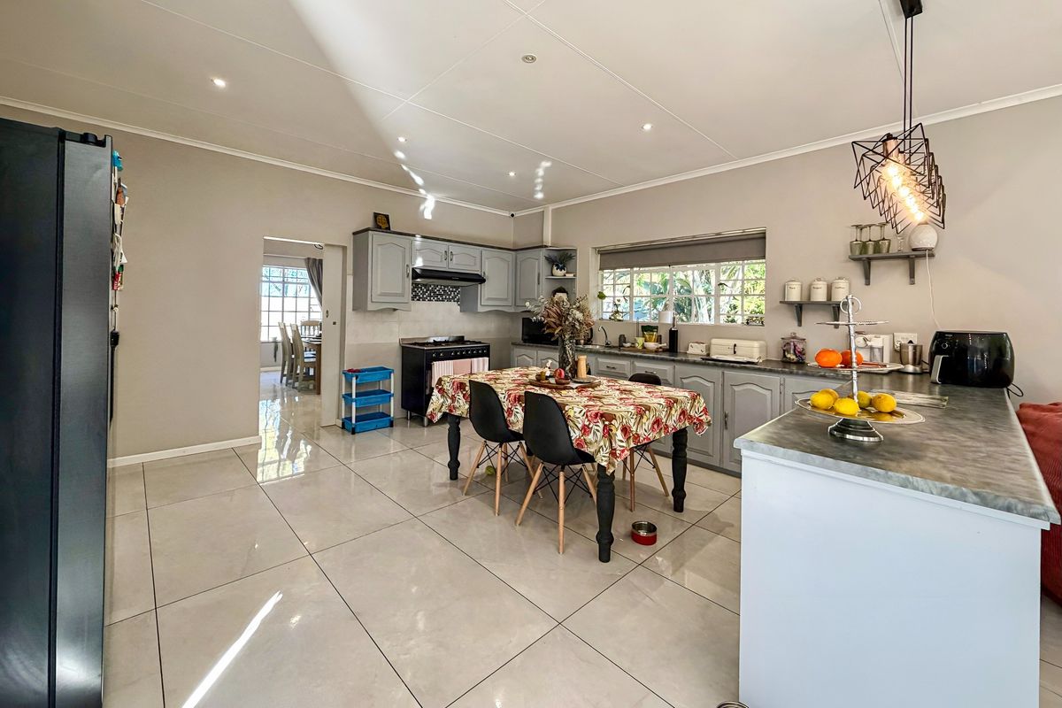 Spacious kitchen featuring grey cabinetry, tiled flooring, a central island, and a gas stove, with an open-plan layout connecting to the dining area.