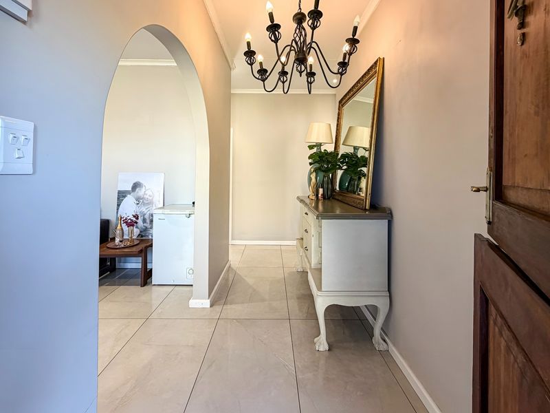 Welcoming entrance hall featuring tiled flooring, an arched transition to the living area, and a classic timber front door.