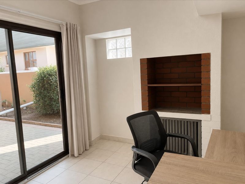 A bright living area featuring tiled flooring, a built-in brick fireplace, and a large sliding glass door providing access to the outdoor patio.