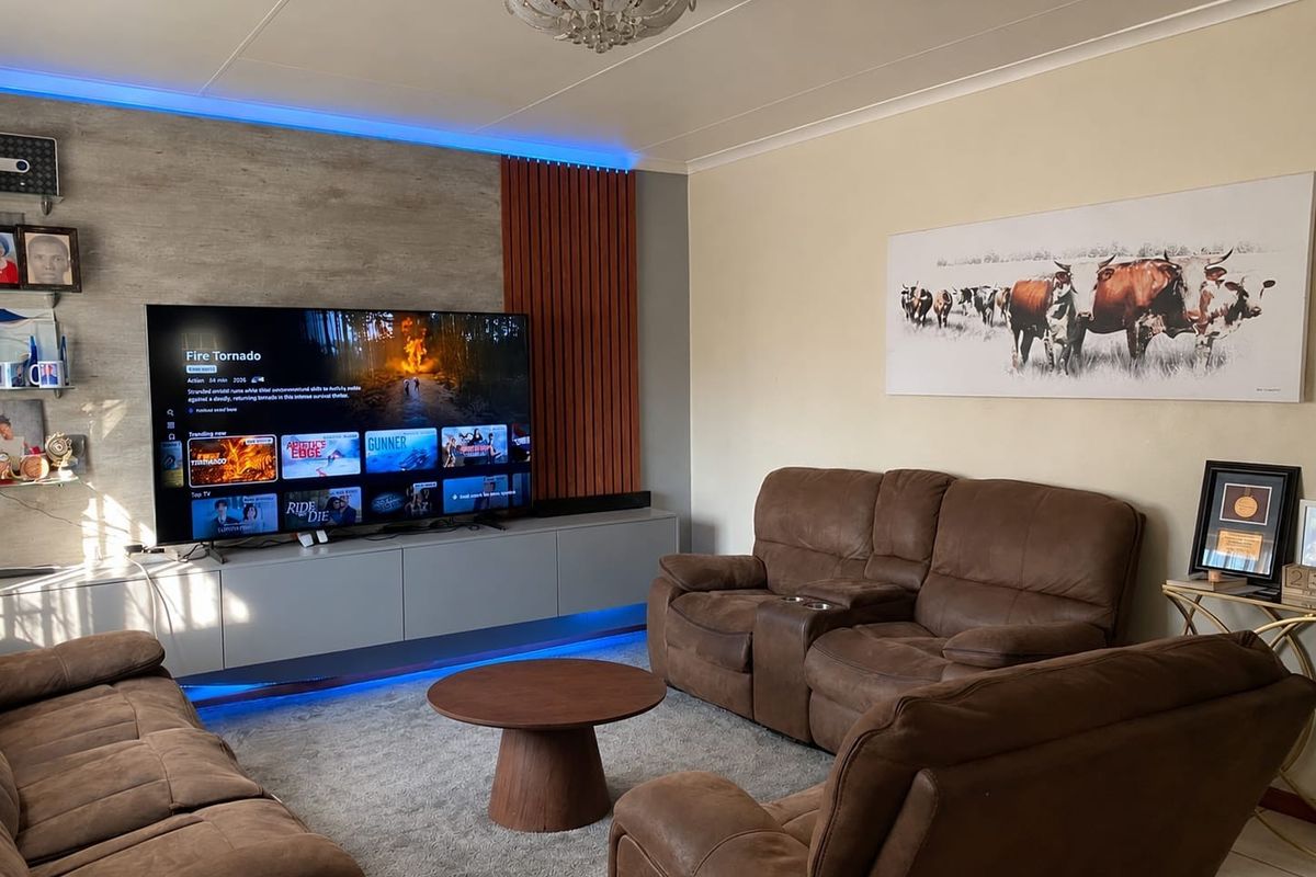 A modern living room featuring a built-in media console with integrated LED accent lighting and decorative wall paneling.