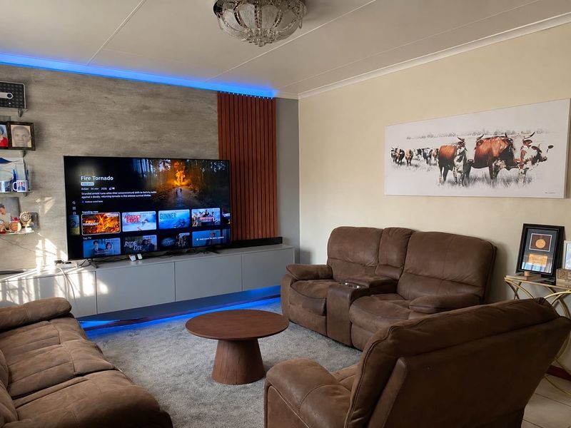 A modern living room featuring a built-in media console with integrated LED accent lighting and decorative wall paneling.