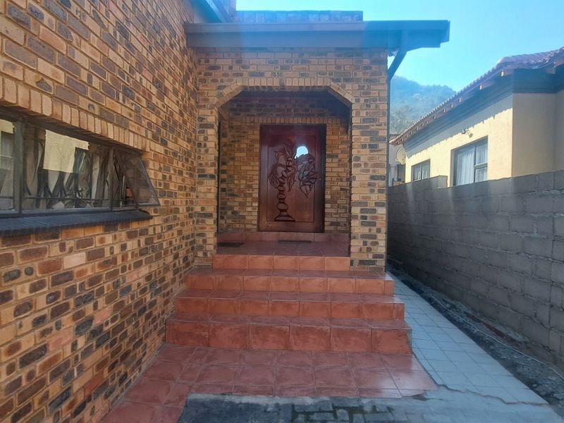 Front entrance featuring a face brick facade, tiled steps, and a decorative carved wooden front door with security gate.