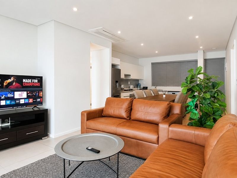 Modern open-plan living and dining area featuring tiled floors, recessed lighting, ducted air conditioning, and a sleek, functional kitchen layout.