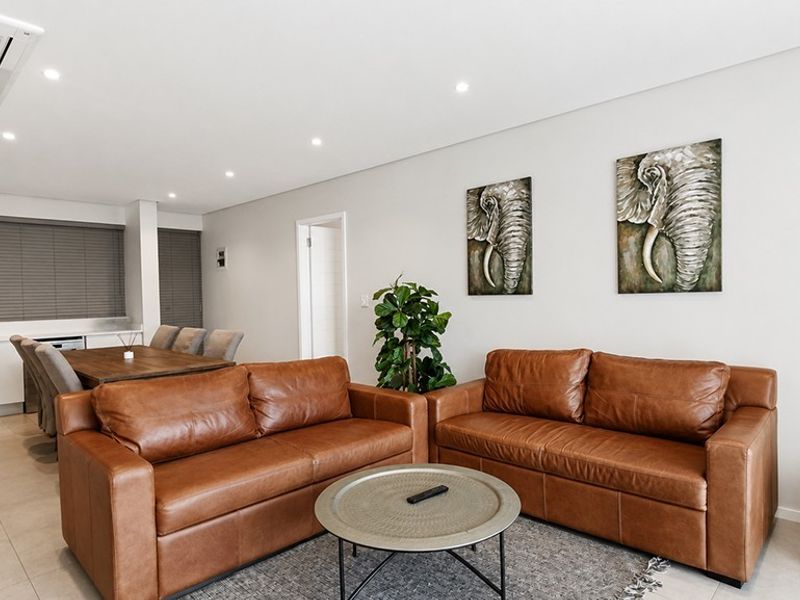 Modern open-plan living and dining area featuring tiled floors, recessed downlighting, ducted air conditioning, and a sleek, minimalist kitchen layout.