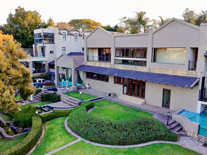 Aerial view of a multi-level residential property featuring a landscaped garden, swimming pool, and expansive outdoor entertainment areas.