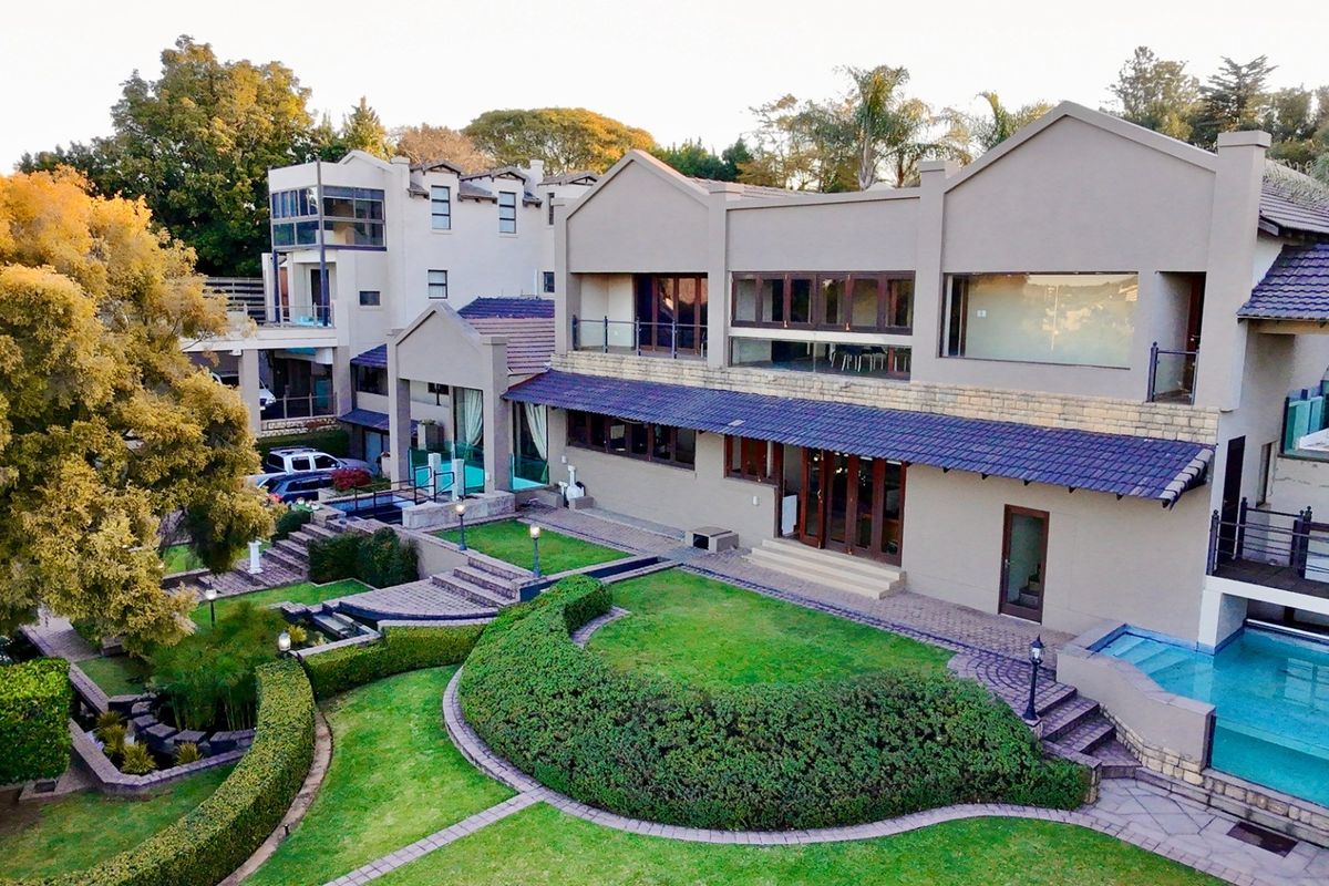 Aerial view of a multi-level residential property featuring a landscaped garden, swimming pool, and expansive outdoor entertainment areas.