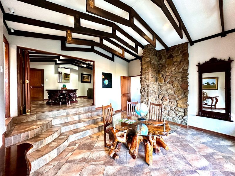 Spacious living area featuring a striking stone fireplace, exposed timber ceiling beams, and elegant tiled flooring with a split-level layout.