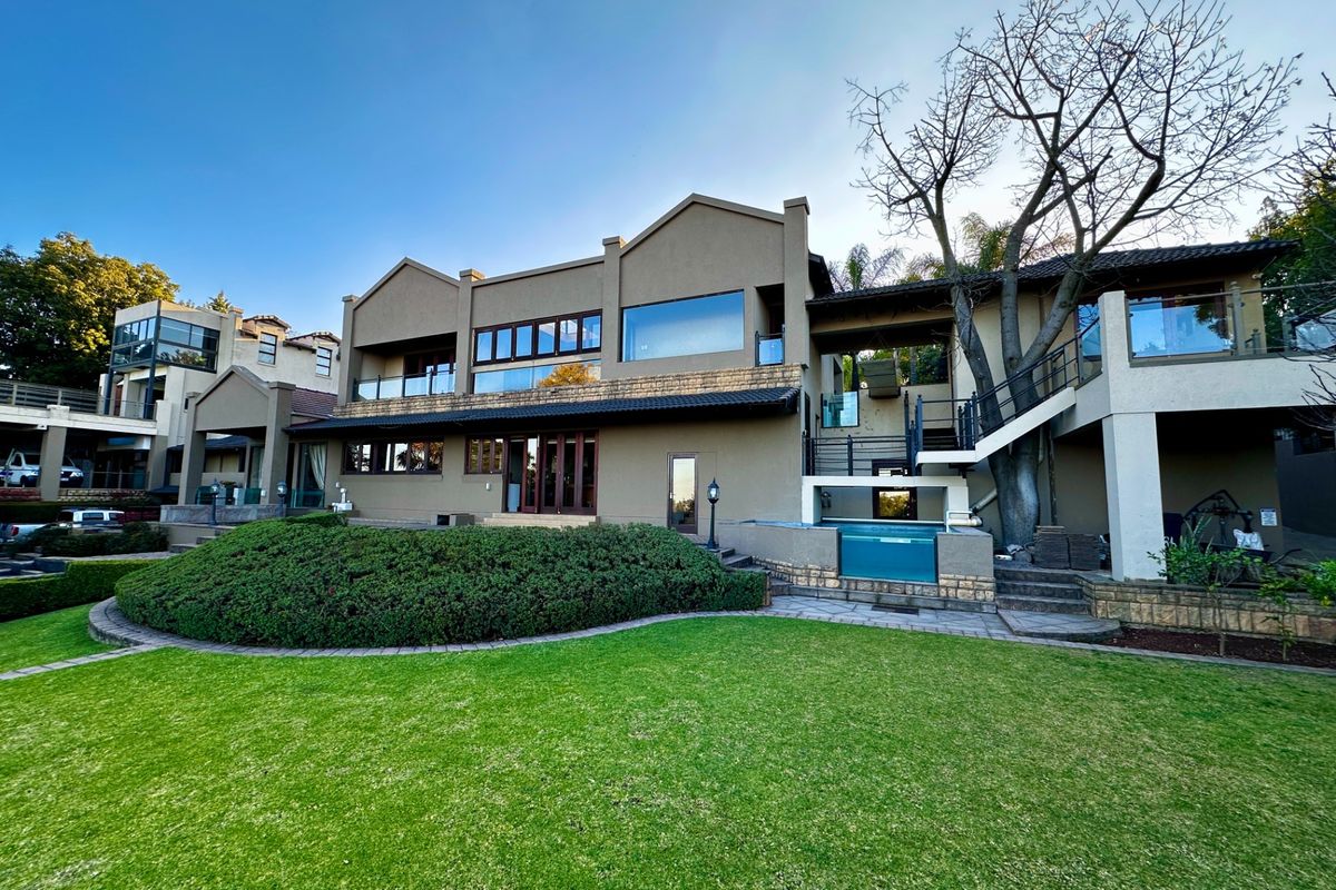 Rear view of a multi-level residence featuring a landscaped garden, swimming pool, stone-clad accents, and elevated balconies with large windows.