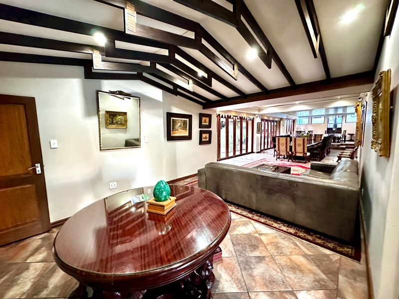 Spacious open-plan living and dining area featuring exposed timber ceiling beams, tiled flooring, and large bi-fold doors leading to the outdoor space.