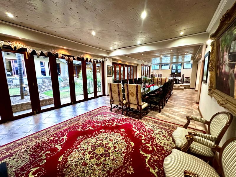 Spacious dining room featuring large bi-fold glass doors opening to the garden, tiled flooring, and recessed lighting, suitable for large gatherings.