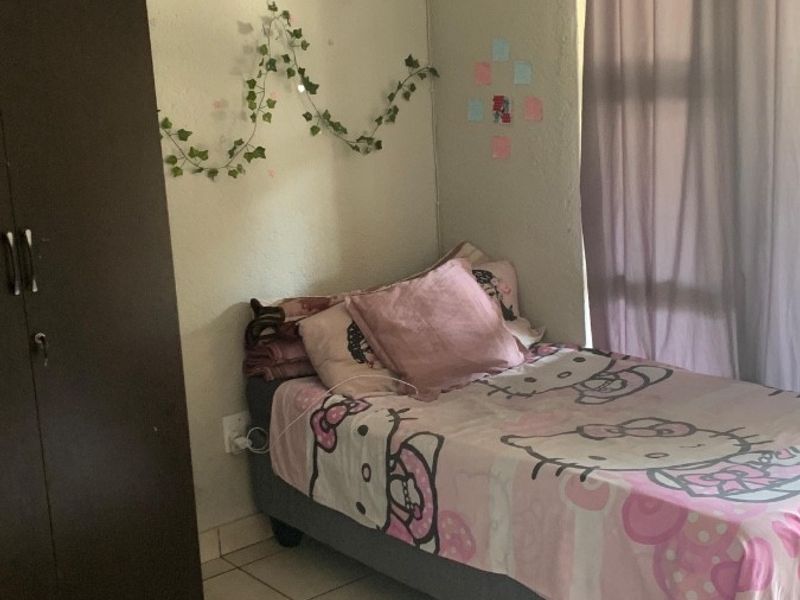 A functional bedroom featuring tiled flooring and a curtain rail, providing a neutral base for personalization.