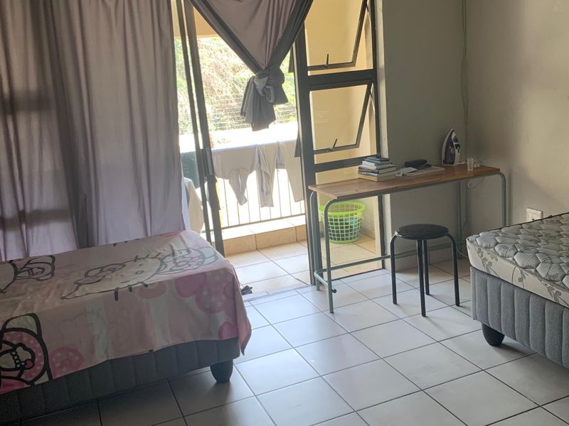 A bedroom featuring tiled flooring and a sliding glass door providing access to a balcony.