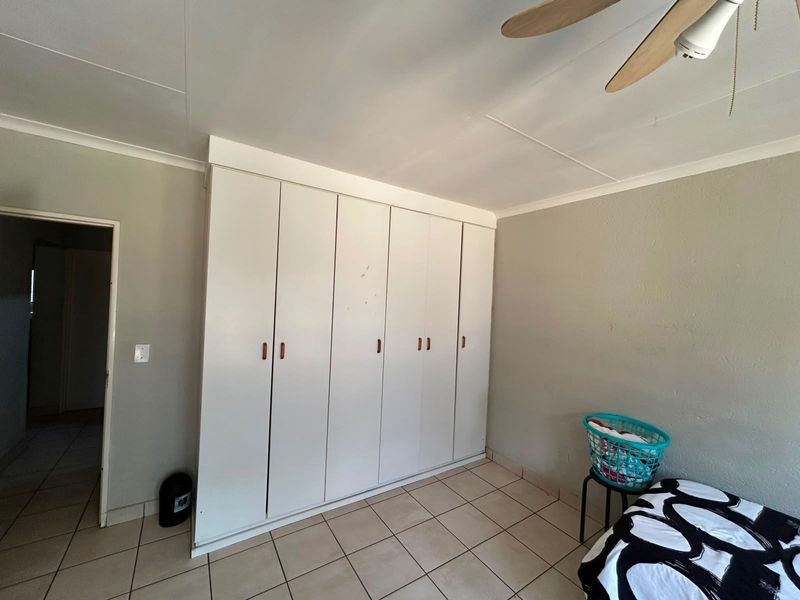 Bedroom featuring tiled flooring, a ceiling fan, and extensive built-in cupboard storage space.