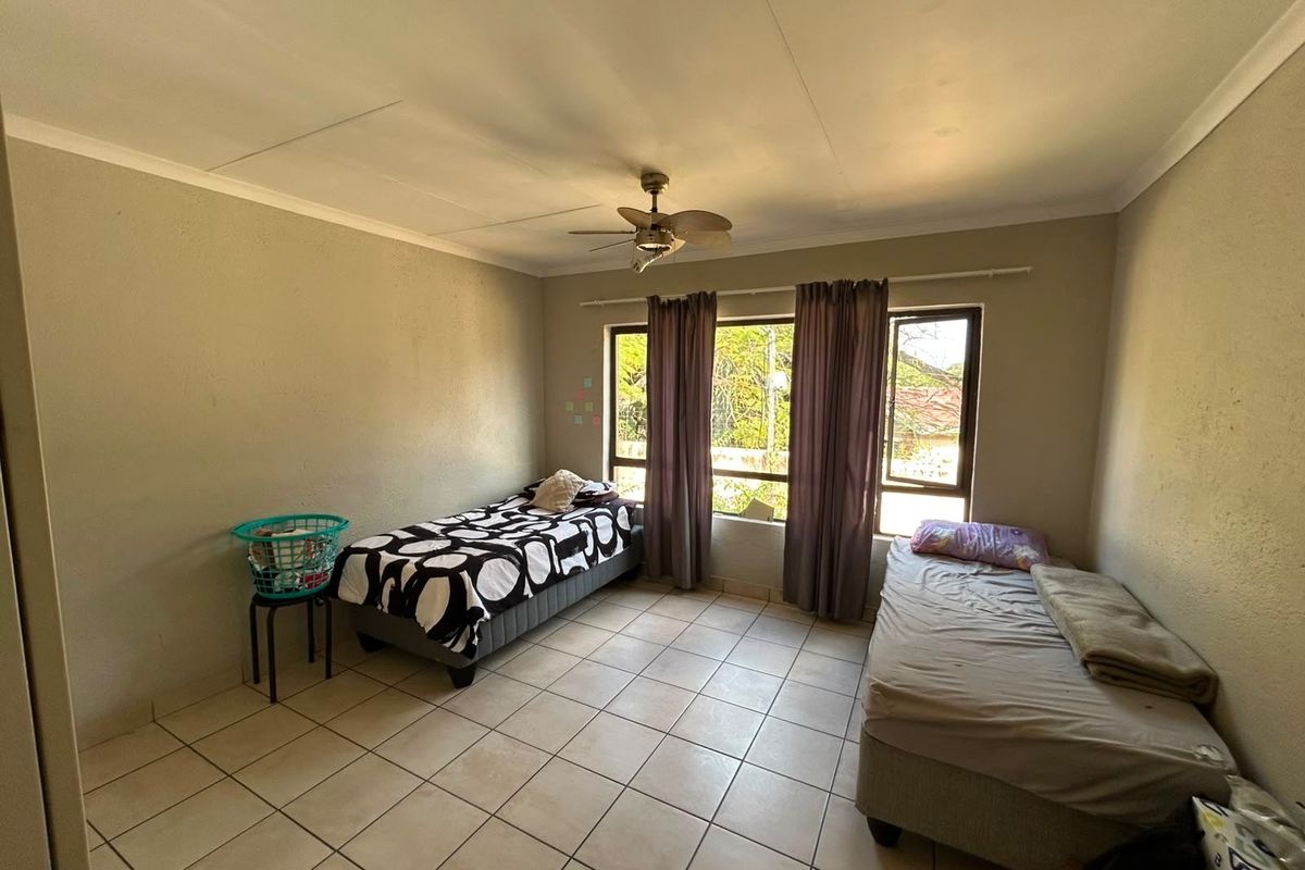 A bedroom featuring tiled flooring, a ceiling fan, and large windows that provide natural light.