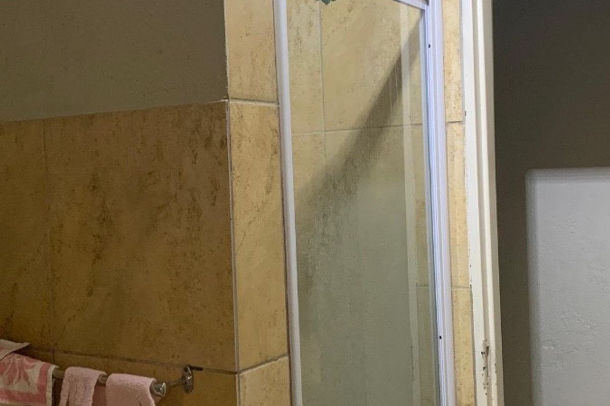 A bathroom featuring a shower enclosure with tiled walls and flooring, requiring some maintenance and cosmetic updates to improve its overall condition.