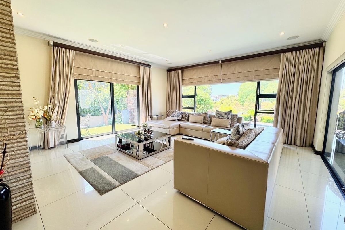 Spacious living room featuring large sliding glass doors, polished tiled flooring, recessed lighting, and a textured stone-clad feature wall.