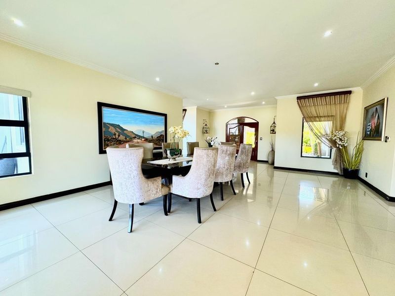 Spacious dining room featuring polished porcelain floor tiles, recessed downlighting, and an elegant arched doorway leading to the entrance.