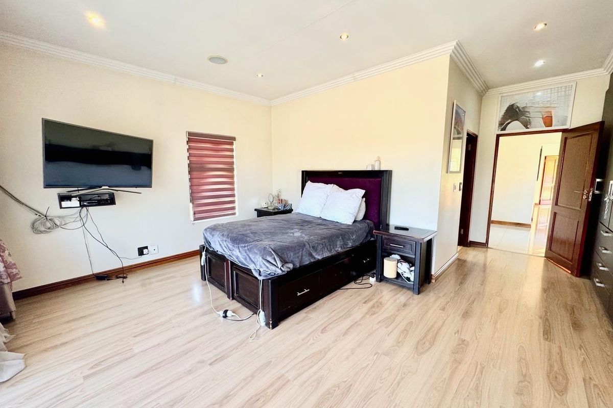 Spacious bedroom featuring light laminate flooring, recessed downlighting, and neutral wall finishes, offering a comfortable and functional living space.