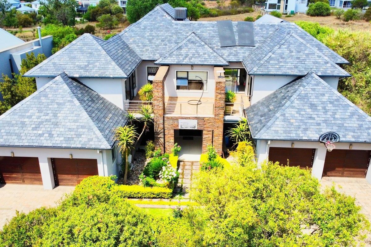 Aerial view of a large residential property featuring a multi-pitched slate roof, stone facade accents, and a spacious paved driveway with double garages.