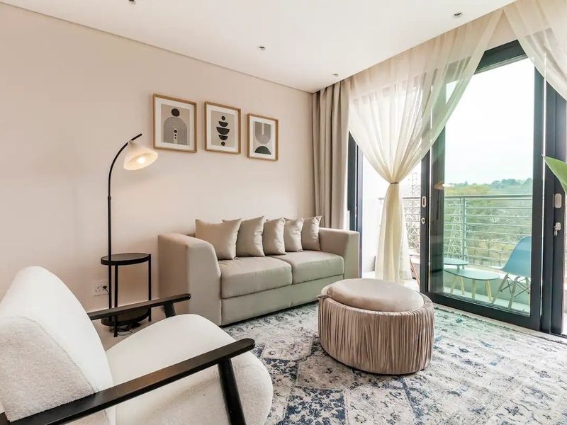 A bright and modern living room featuring tiled flooring, recessed lighting, and a large sliding glass door providing access to a balcony.