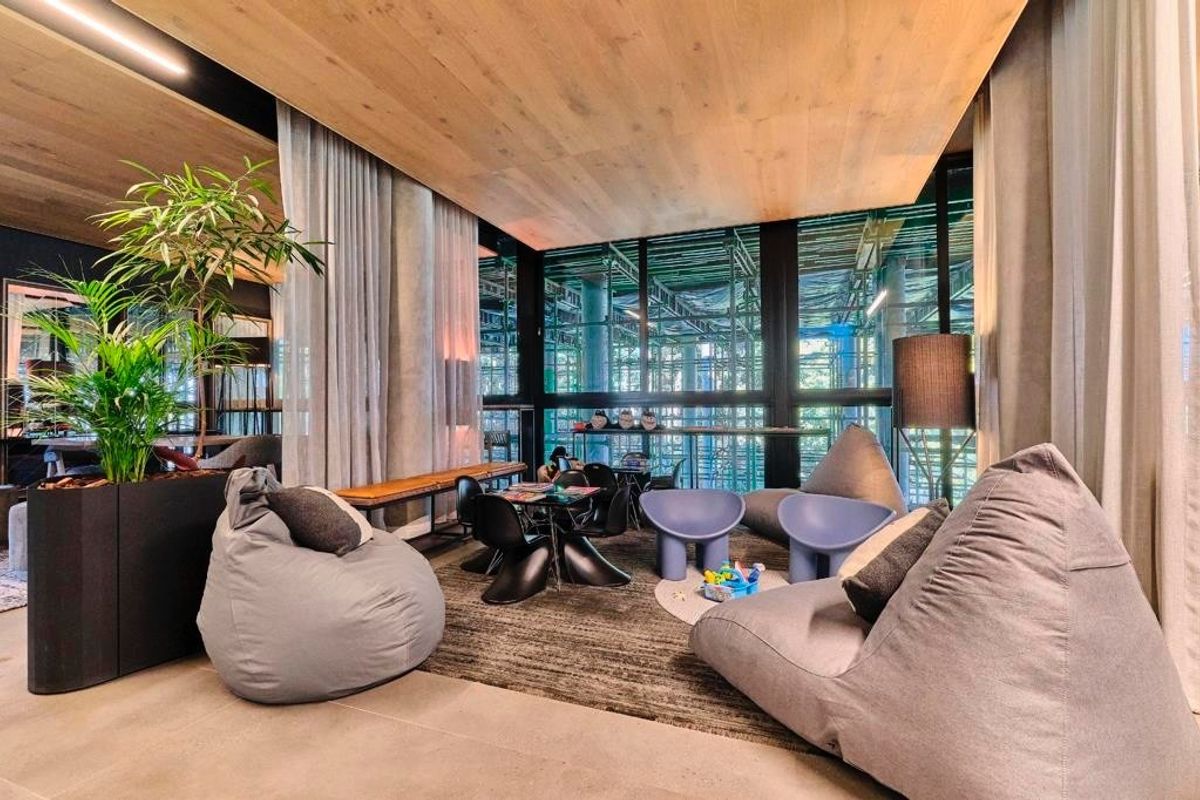 Modern living area featuring a warm timber ceiling, polished concrete floors, and expansive floor-to-ceiling windows providing ample natural light.