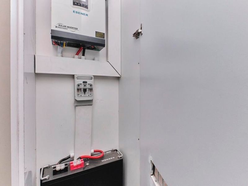 A dedicated utility cupboard housing a solar inverter and battery storage system, neatly integrated into the apartment's infrastructure.