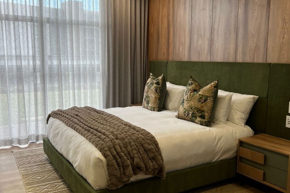 A modern, well-appointed bedroom featuring wood-paneled accent wall, split-system air conditioning, and floor-to-ceiling window treatments.