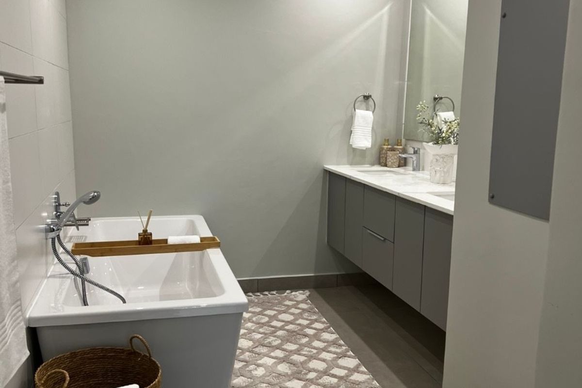 Modern bathroom featuring a sleek freestanding bathtub, wall-mounted double vanity, and contemporary tiled finishes with recessed lighting.