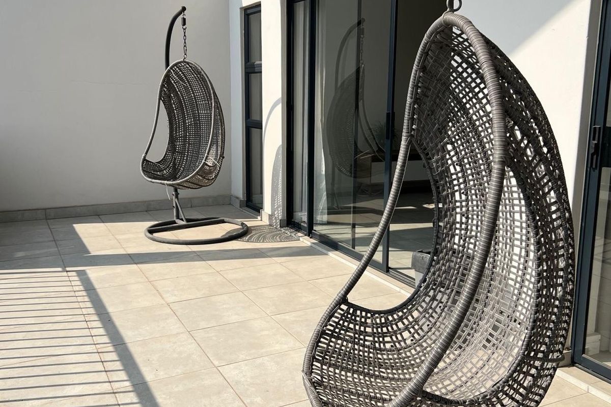 A spacious, tiled balcony featuring modern sliding glass doors and a metal balustrade, offering a clean and well-maintained outdoor living space.