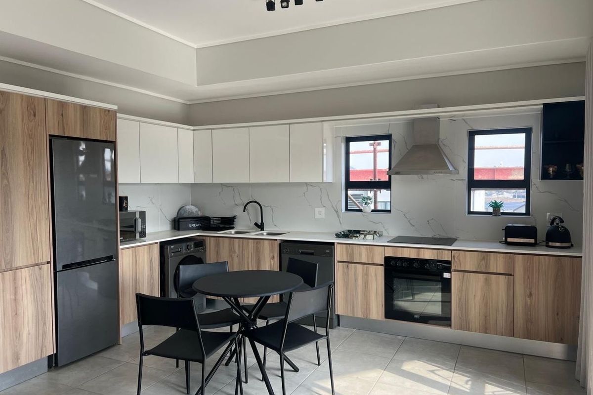Modern kitchen featuring wood-grain and white cabinetry, stone-look backsplash, integrated oven, electric hob, and sleek track lighting in a well-maintained open-plan layout.
