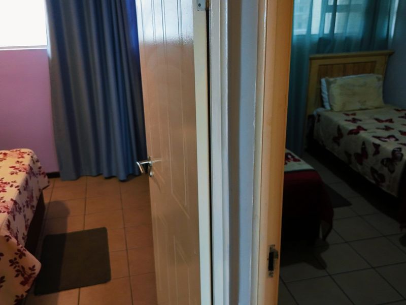 A view looking through an open doorway into a bedroom with tiled flooring.