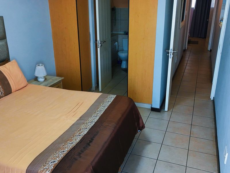 Bedroom featuring tiled flooring and built-in cupboards, with direct access to an en-suite bathroom.