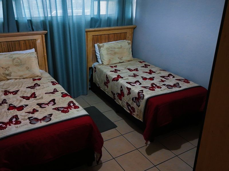 A functional bedroom featuring tiled flooring and window treatments, providing a comfortable space for residents.