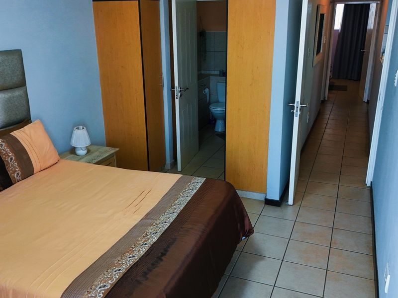 Bedroom featuring tiled flooring and built-in cupboards, with direct access to an en-suite bathroom.