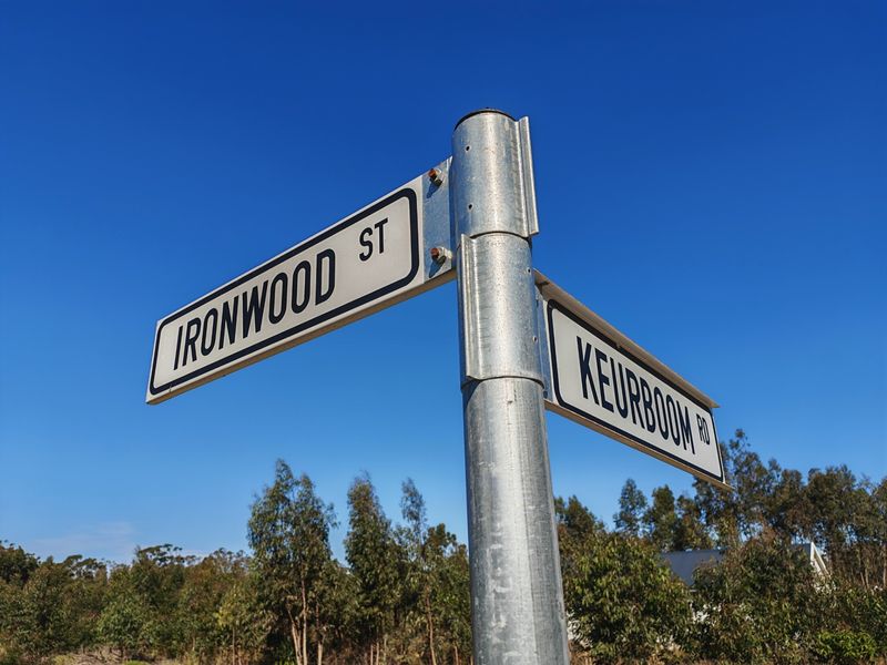 A clear street sign indicating the intersection of Ironwood Street and Keurboom Road, set against a clear blue sky.
