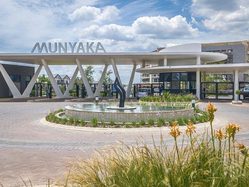 The main entrance to the Munyaka estate, featuring a modern security gatehouse, paved driveway, and a central water feature.