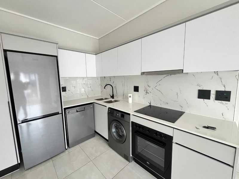 Modern kitchen featuring white cabinetry, marble-look splashback, integrated appliances, and sleek black fixtures.