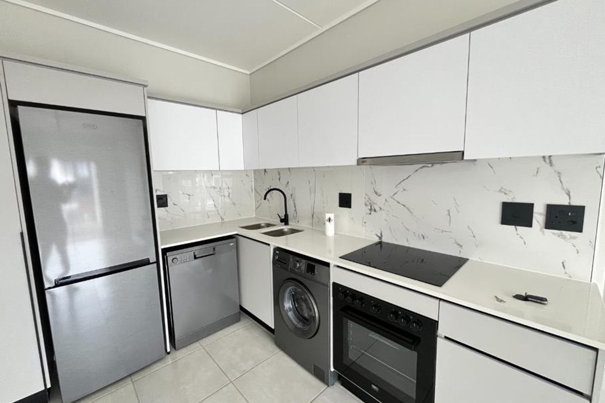Modern kitchen featuring white cabinetry, marble-look splashback, integrated appliances, and sleek black fixtures.