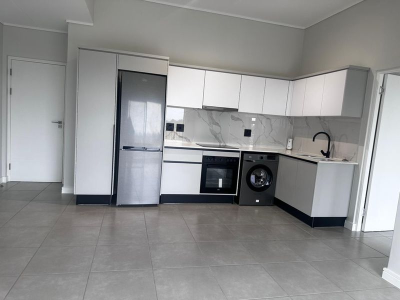 Modern kitchen featuring white cabinetry, marble-look splashback, integrated appliances, and neutral tiled flooring in a clean, contemporary apartment setting.