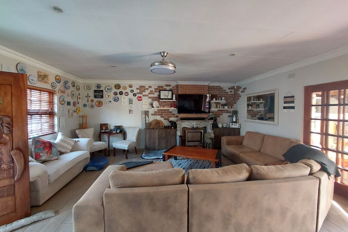 Spacious living room featuring a prominent brick fireplace, tiled flooring, and a ceiling fan, offering a comfortable and inviting atmosphere.