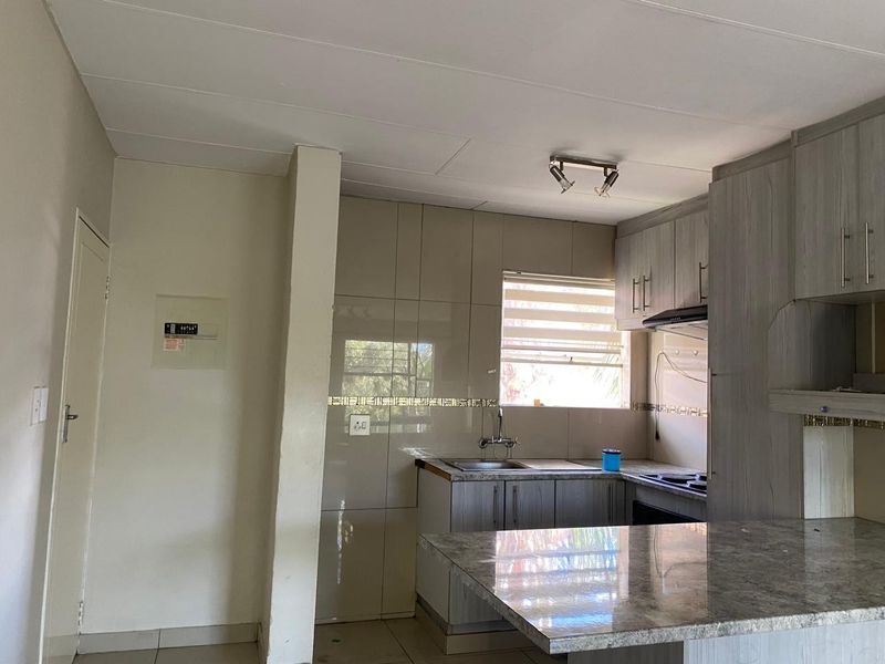 A functional kitchen featuring built-in cabinetry, stone-look countertops, a stainless steel sink, and a tiled backsplash, offering a clean and practical workspace.