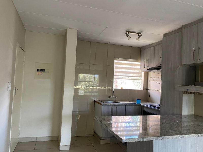 A functional kitchen featuring built-in cabinetry, stone countertops, a tiled backsplash, and integrated cooking appliances, offering a clean and practical workspace.
