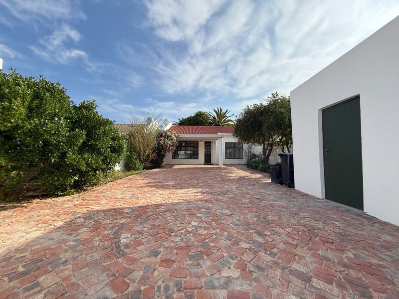 Front view of the property featuring a circular pattern brick paved driveway leading to the main entrance and a tiled roof.