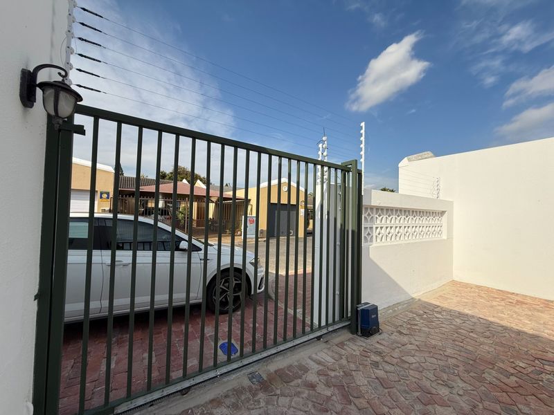 Front entrance area featuring a secure electric gate, perimeter electric fencing, and brick-paved driveway with a decorative boundary wall.