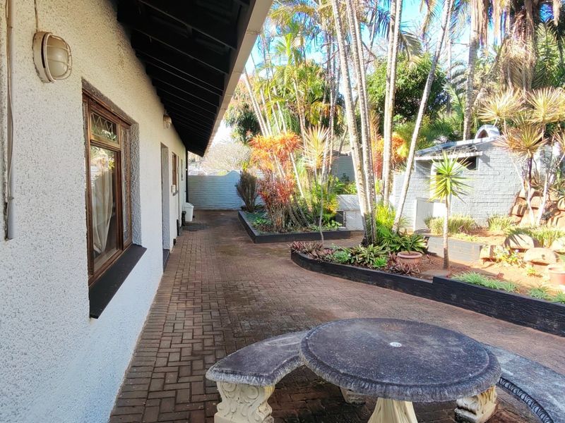 A paved outdoor patio area featuring retaining walls and established garden landscaping, providing a functional space for outdoor relaxation.