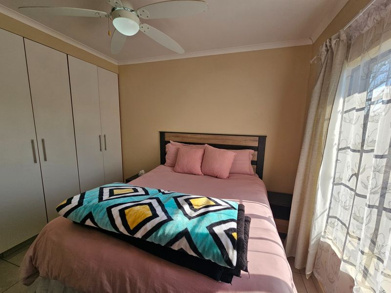 A functional bedroom featuring built-in cupboards and a ceiling fan, offering a comfortable and practical living space.