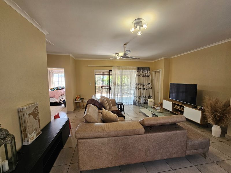 Spacious living room featuring tiled flooring, ceiling fan, and direct access to an outdoor patio area through sliding glass doors.