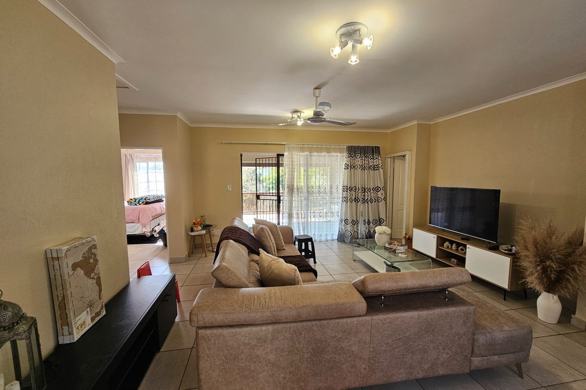 Spacious living room featuring tiled flooring, ceiling fan, and direct access to an outdoor patio area through sliding glass doors.